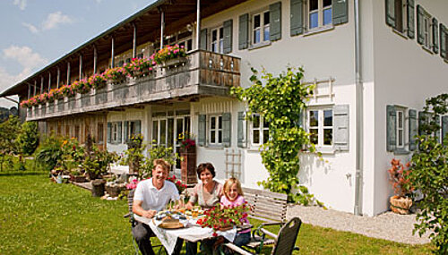 Familie am Tisch vor dem Wohnhaus