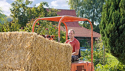 Betriebsleiter auf Gabelstapler mit Strohballen