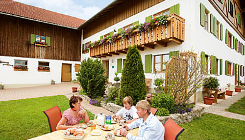 Familie am Esstisch vor dem Wohnhaus