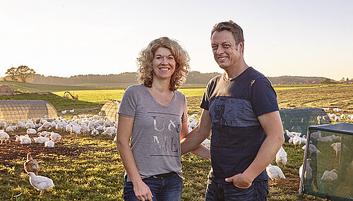 Man und Frau auf Feld mit Hühnern